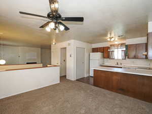 Kitchen with a sink, freestanding refrigerator, dark colored carpet, and light countertops