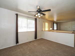 Spare room with carpet, visible vents, and a ceiling fan