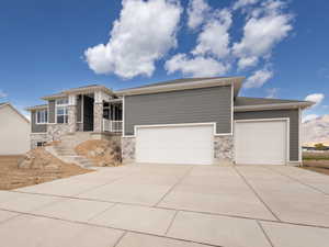 Prairie-style house featuring an attached garage, stone siding, and concrete driveway