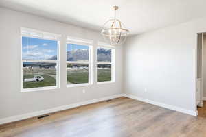 Unfurnished room featuring baseboards, a chandelier, visible vents, and light wood-type flooring