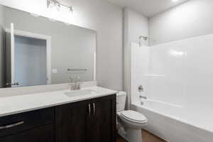 Bathroom featuring wood finished floors, toilet, vanity, and shower / tub combination