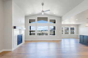 Unfurnished living room featuring recessed lighting, a glass covered fireplace, light wood-style floors, and ceiling fan with notable chandelier