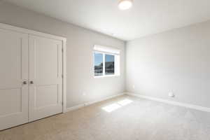 Unfurnished bedroom with carpet floors, a closet, and baseboards