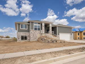 Prairie-style home featuring an attached garage, driveway, and stone siding