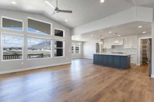Kitchen with white cabinets, light countertops, premium range hood, freestanding refrigerator, and open floor plan