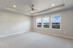 Empty room with ceiling fan, light carpet, a raised ceiling, baseboards, and recessed lighting