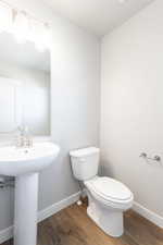 Bathroom with a sink, toilet, wood finished floors, and baseboards