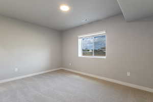 Carpeted spare room featuring baseboards and visible vents