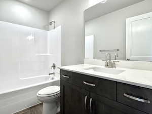 Full bath featuring shower / bathtub combination, wood finished floors, vanity, and toilet