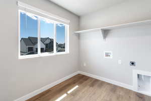 Laundry room with laundry area, wood finished floors, hookup for a washing machine, baseboards, and electric dryer hookup