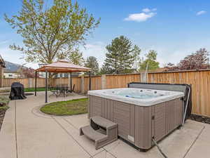 View of patio featuring a gazebo, a hot tub, and a fenced backyard