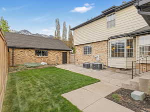 Rear view of property featuring brick siding, central AC, and a patio