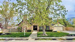 Obstructed view of property with fence, brick siding, and a front yard