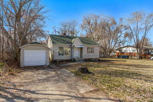 View of front of house featuring a chimney, fence, a shingled roof, driveway, and a detached garage
