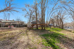 View of yard featuring a deck, stairs, and fence