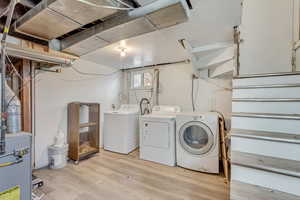 Washroom with independent washer and dryer, light wood-type flooring, and laundry area
