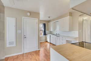 Kitchen with white cabinets, light wood finished floors, light countertops, and a sink