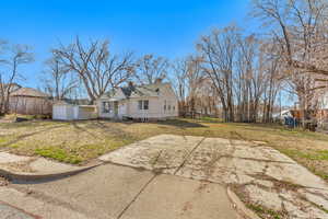View of side of property featuring a chimney, fence, an outbuilding, a detached garage, and a lawn