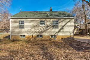 Back of house with fence, a chimney, and a shingled roof