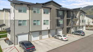 View of front of property featuring driveway, a mountain view, an attached garage, stucco siding, and central AC unit