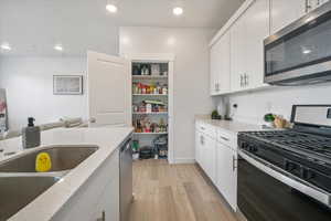Kitchen featuring recessed lighting, light wood-style flooring, stainless steel appliances, and white cabinetry