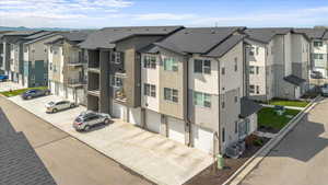 View of property featuring a residential view, concrete driveway, and an attached garage