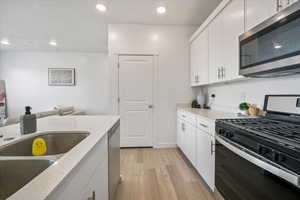 Kitchen featuring recessed lighting, white cabinets, light wood-style flooring, and stainless steel appliances