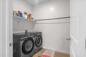 Laundry room featuring independent washer and dryer, light wood-style flooring.