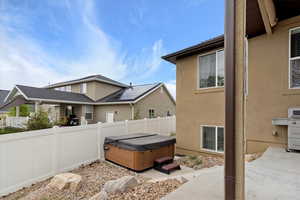 View of home's exterior featuring fence, stucco siding, a hot tub, and a patio area