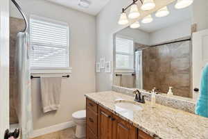 Full bath featuring a shower with curtain, vanity, tile patterned floors, toilet, and baseboards