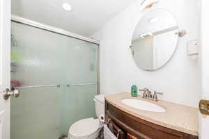 Bathroom featuring toilet, visible vents, a shower stall, and vanity
