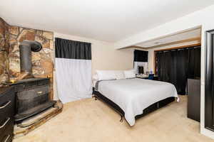Bedroom with a wood stove and light carpet