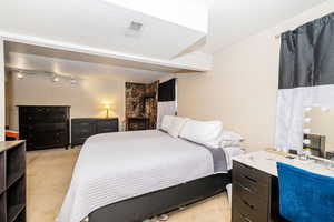 Bedroom featuring a wood stove, visible vents, and light colored carpet