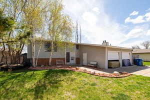 View of front facade featuring a front lawn, concrete driveway, and an attached garage