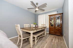 Dining space featuring a ceiling fan, baseboards, and light wood-style floors