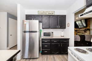 Kitchen featuring light wood finished floors, backsplash, stainless steel appliances, and light countertops