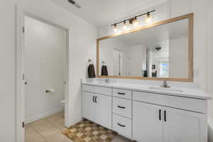 Full bath with double vanity, visible vents, toilet, and a sink