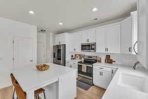 Kitchen with visible vents, light wood-style floors, a kitchen bar, light countertops, and appliances with stainless steel finishes