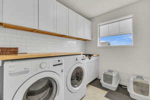 Clothes washing area with baseboards, independent washer and dryer, light tile patterned floors, and cabinet space