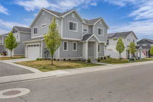 View of front of property with board and batten siding, an attached garage, driveway, and a residential view
