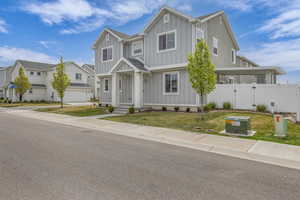 View of front of house featuring board and batten siding, an attached garage, a front yard, and fence