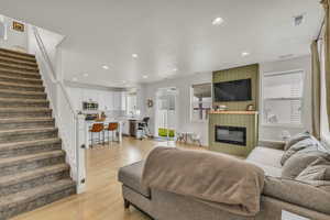 Living area featuring recessed lighting, visible vents, light wood-type flooring, a fireplace, and stairs