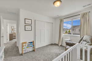 Carpeted bedroom with baseboards, visible vents, and a closet