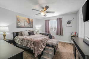 Bedroom featuring a textured ceiling, ceiling fan, carpet flooring, and baseboards