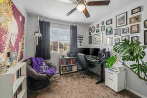 Carpeted office featuring baseboards, ceiling fan, and a textured ceiling