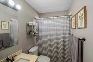 Bathroom with a textured ceiling, vanity, toilet, and curtained shower