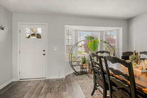 Foyer with a textured ceiling, visible vents, wood finished floors, and baseboards