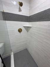 Full bath featuring toilet and a tile shower