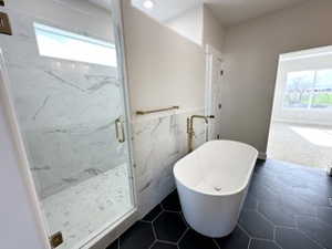 Full bathroom featuring a freestanding tub, a wealth of natural light, tile walls, and a marble finish shower