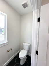 Bathroom featuring toilet, tile patterned flooring, visible vents, and baseboards